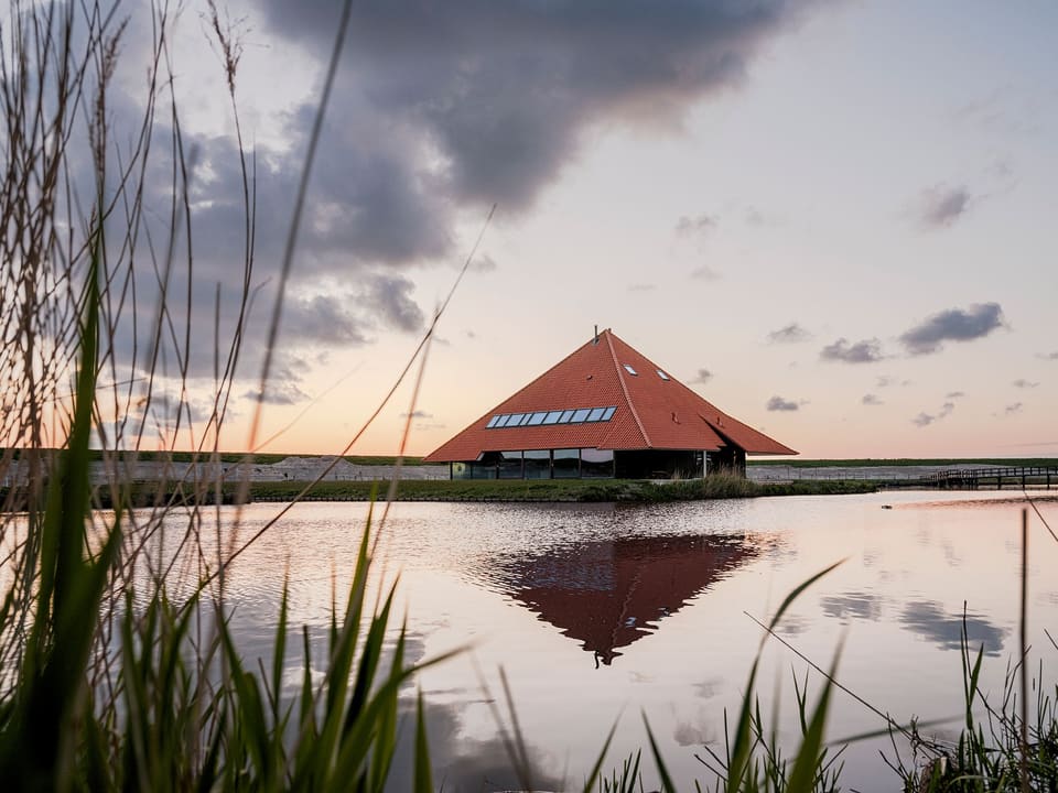 De stolp in de schemering, gespiegeld in het water, met riet op de voorgrond