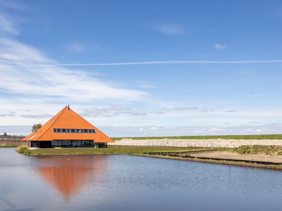 De stolp spiegelt zich in het water onder een blauwe lucht